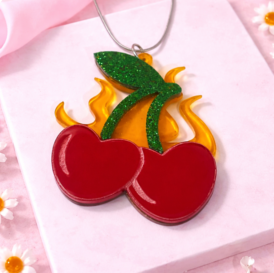 Flaming cherry statement necklace on pink flat lay backgroun