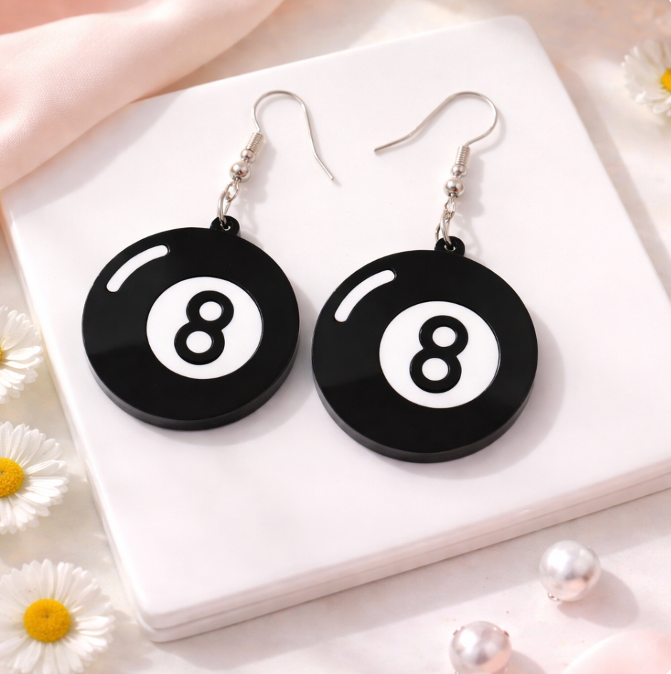 Black and white 8 ball acrylic dangle earrings with silver hooks on a soft neutral background
