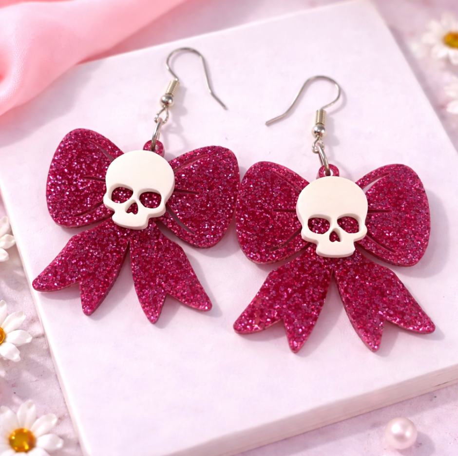 Pink glitter skull bow earrings featuring skull detail, lightweight acrylic statement earrings