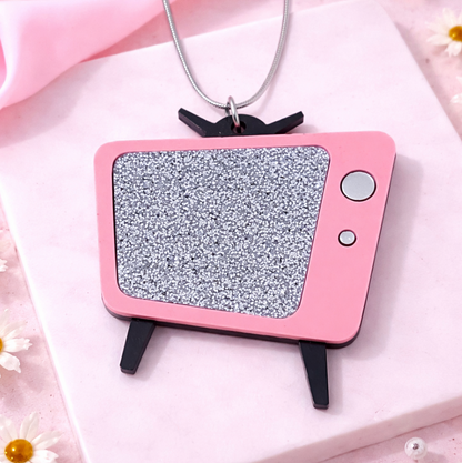 Pink retro TV necklace with glitter screen on soft pink flat lay background