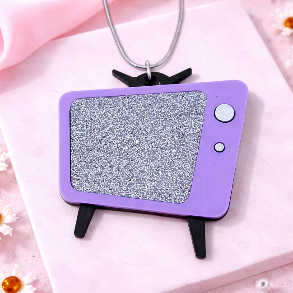 Purple retro TV necklace with glitter screen photographed on pink tile background