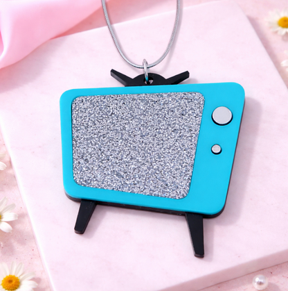 Turquoise Teal retro TV necklace with glitter screen on pink flat lay background