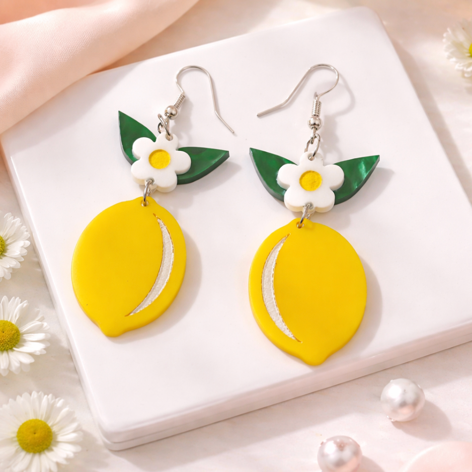 Handmade lemon statement earrings in acrylic with green leaves and white flower on neutral background